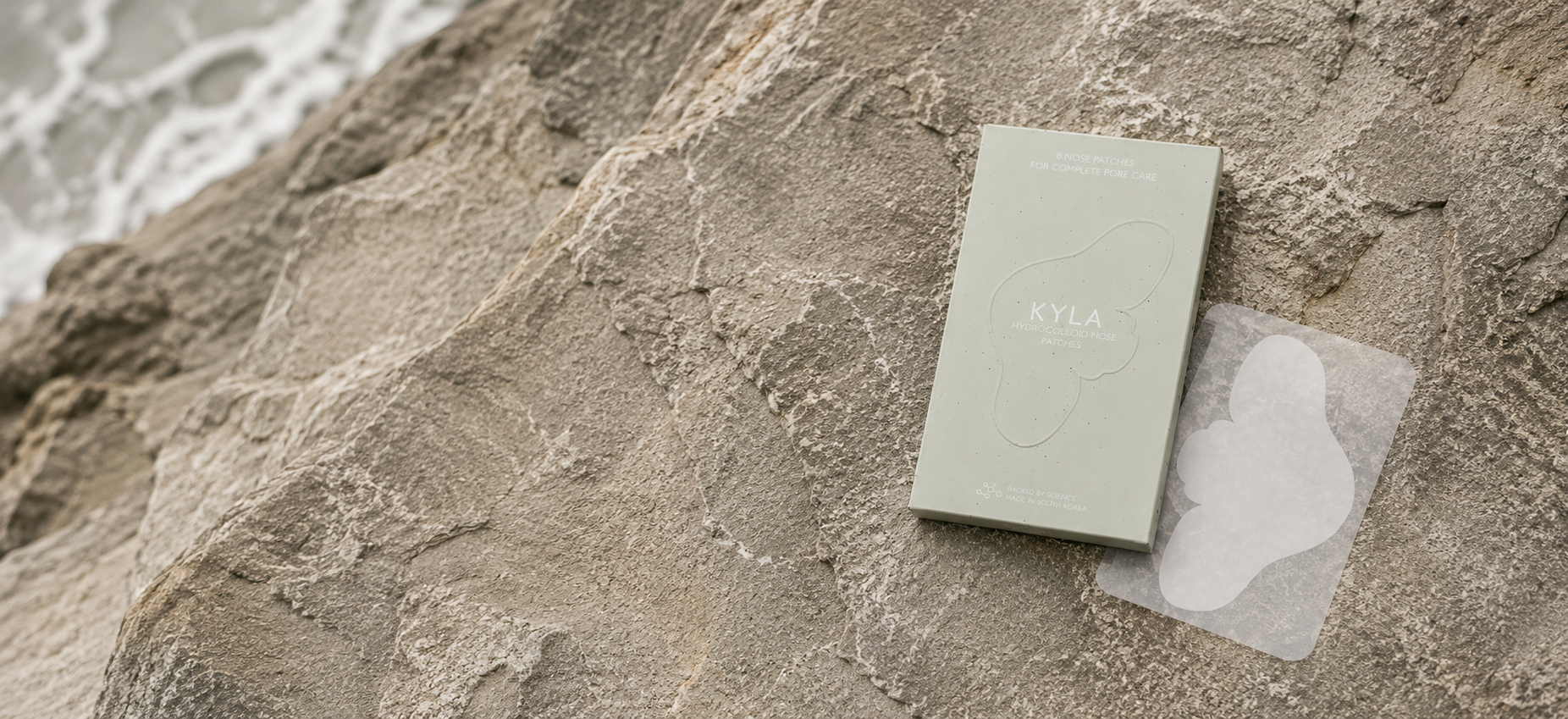 KYLA hydrocolloid patch and its sage-green box on a light stone surface
